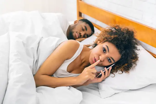アフリカ系アメリカ人の若い女性はベッドに横たわり 男性は彼女の横で眠り 現代の関係のダイナミクスをヒント — ストック写真