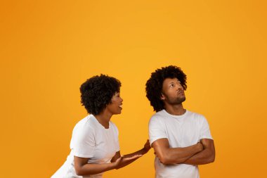 Boşanma, ayrılma, evlilikteki kriz. Duygusal genç Afrikalı Amerikalı kadın, sarı stüdyo arka planında izole edilmiş, rahatsız kocasıyla veya erkek arkadaşıyla konuşuyor, kafalarının üstündeki boşluğu kopyalıyor.