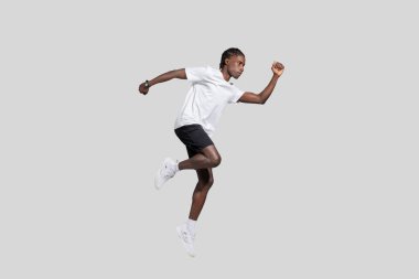 Young African American guy with athletic build captured in mid-air, exemplifying dynamics and energy against a plain background clipart