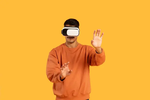 Guy Immersed Virtual Reality Wearing Headset Gesturing Hands Vibrant Orange — Stock Photo, Image
