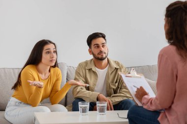 Bu görüntü, terapistle konuşurken şaşkın bakışlı genç bir çifti bir seansta, aile terapisinde yakalıyor.