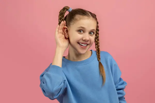 一个对耳朵很注意的女孩在一个鲜亮的粉色背景下模仿听或听什么东西 — 图库照片