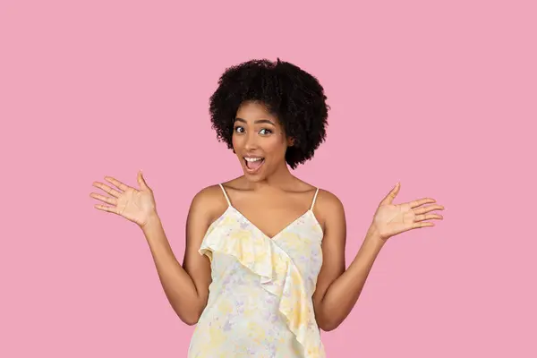 快乐而漂亮的非洲裔美国女人 穿着华丽的衣服 张开双臂 脸上带着惊讶的粉色背景 — 图库照片