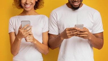 Siyah bin yıllık çift ağ veya arkadaş, turuncu arka plan ile sohbet cep telefonları üzerinde tarama