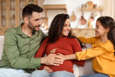 Neşeli bir aile, babası, hamile annesi ve kızı ile birlikte sıcacık bir evde güzel vakit geçiriyorlar.