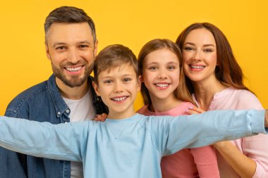 İki çocuk ve mutlu ebeveynle sıkı bir aile kucaklaşması, dört mutlu yüzü yakından görmek, selfie çekmek.