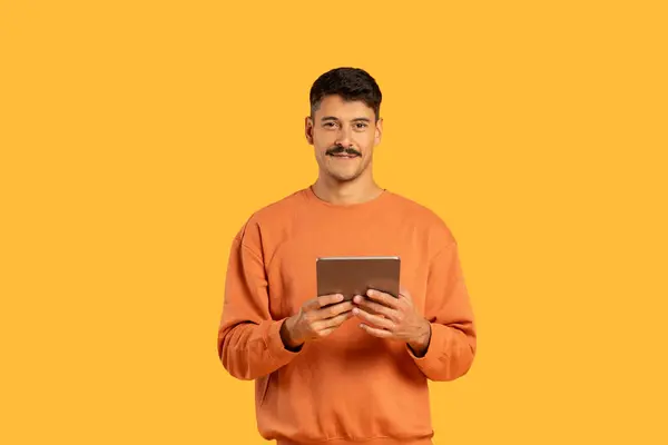 Homem Alegre Vestindo Uma Camisola Laranja Segura Tablet Com Sorriso — Fotografia de Stock