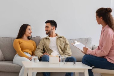 Genç bir çift kanepede oturup birbirleriyle sohbet ederken bir yandan da elinde not panosu olan bir kadın terapist terapi seansı sırasında dinleyip gözlemliyor.