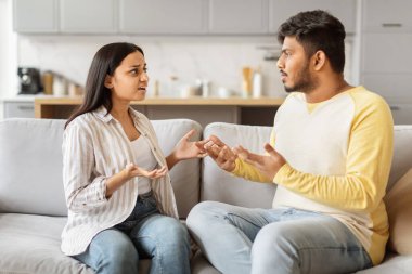 Kanepede oturan Hintli erkek ve kadın ciddi bir konuşma içinde gibi görünüyor, potansiyel bir anlaşmazlık.