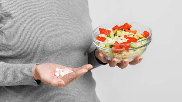 Ältere Europäerin Erwägt Medikamente Oder Gesunde Ernährung Auf Grauem Hintergrund — Stockfoto