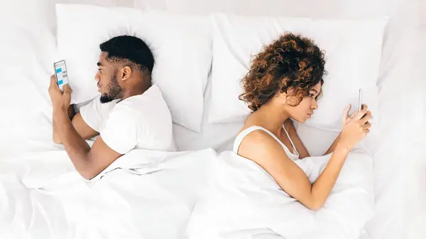 千禧一代夫妇在争吵中 背靠背躺在床上 使用智能手机 不注意对方 顶视图 — 图库照片