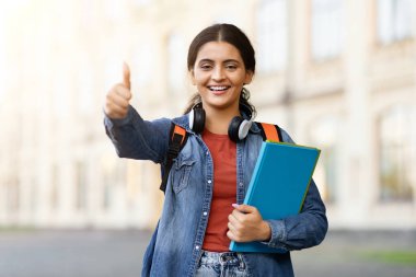 Kitapları olan Hintli bir bayan, Hindu bir yakınlaştırıcıya uygun eğitim kampüsü ortamında onaylama ve pozitiflik tasvir ediyor.