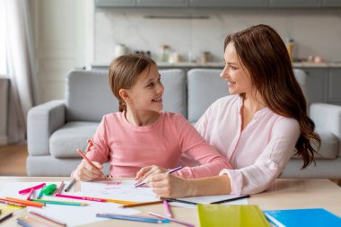 Bu resim, bir anne ve kızın evde birlikte resim çizerek sevgi ve sevgiyi paylaştığı Avrupalı bir aile sahnesini gözler önüne seriyor.