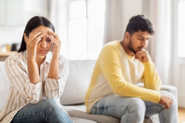 Üzgün bir Hintli kadın, hayal kırıklığına uğramış bir adamın yanında oturuyor. İkisi de kanepede oturuyor ve ilişki sorunlarını gösteriyor.