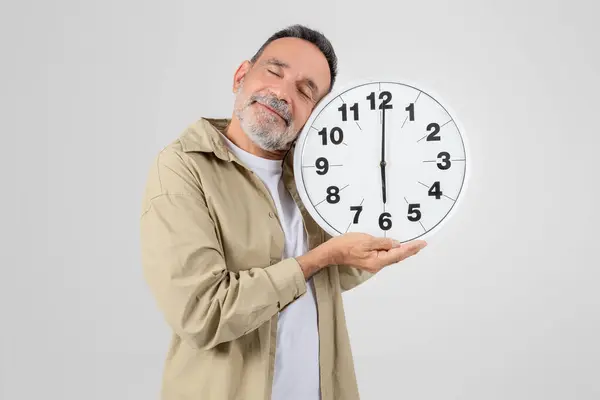 一位老人把一个大钟放在他面前 被白色背景隔离 象征着时间和衰老的概念 — 图库照片