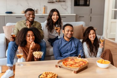Çeşitli arkadaşlar bir masanın etrafında toplanır pizza ve şarabın tadını çıkarırlar, rahat bir evde arkadaşlığı ve boş zamanı sembolize ederler.