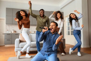 Ateşli bir şarkıcıyla enerjik bir karaoke performansı ve evde dans eden ve eğlenen çok ırklı arkadaşlar.
