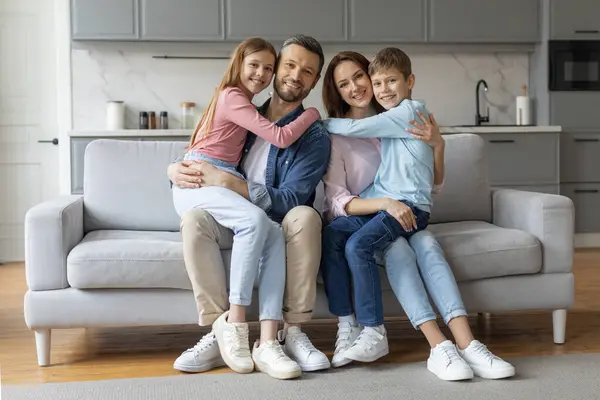 Cheerful Family Two Children Sitting Closely Grey Couch Smiling Camera — Stock Photo, Image
