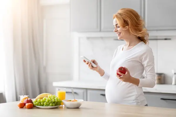 Görüntü Sağlıklı Yiyecek Seçenekleriyle Çevrili Zeki Bir Mutfakta Akıllı Telefonuyla — Stok fotoğraf