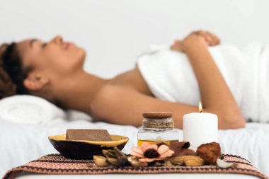 An African American lady exhibits tranquility during a spa massage session with essential oils and candles clipart