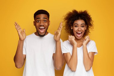 Mutlu bir şekilde kameraya, çığlık heyecanlı Afrikalı-Amerikalı çift tutmak ellerini kaldırdı, turuncu arka plan