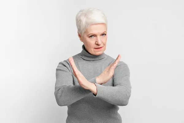 一个年长的欧洲裔妇女 用胳膊做X号手势 表示不愿意或不愿意停歇一生 — 图库照片