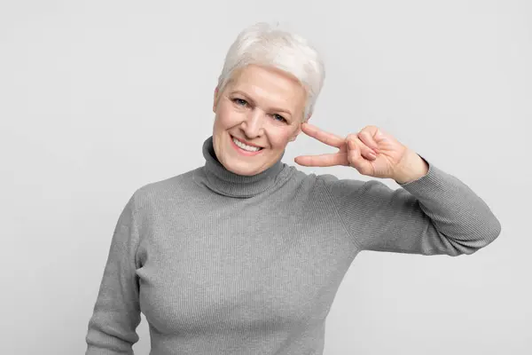 Cheerful Senior European Woman Flashes Peace Sign Her Eye Portraying — Stock Photo, Image