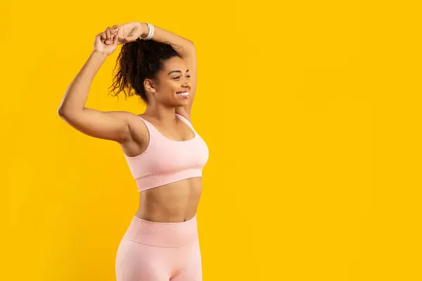 アフリカ系アメリカ人女性は フィットネステーマのための黄色の背景に単離された柔軟性と強さを示すストレッチを実行します — ストック写真