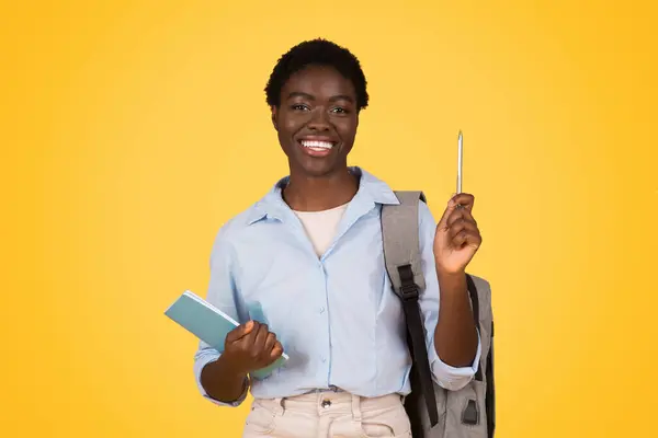 陽気なアフリカ系アメリカ人の学生が上向きに指摘し ズーマー世代によって象徴される楽観主義と上向きのモビリティを示しています — ストック写真