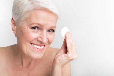 Yaşlı Avrupalı kadın gülümserken pamuk yastık sunuyor, hijyen ve neşeli s3niorlife anları yansıtıyor