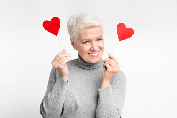 Uśmiechnięta Starsza Europejka Trzymająca Dwa Kije Sercowe Ucieleśniająca Kochające Czułe — Zdjęcie stockowe