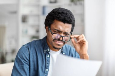Afro-Amerikalı bir adam evrak işlerini incelemeye dalmış, çalışkanlık ve sorumluluk yönetimine işaret ediyor.