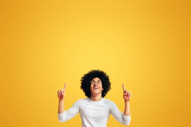 Neşeli bin yıllık Afrikalı-Amerikalı adam yukarı doğru kopya alanı turuncu studio zemin üzerine işaret