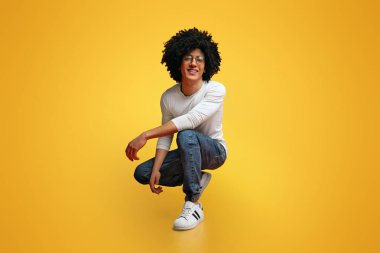 Benim tarzım. Genç siyah adam aşağı hunkering ve gülümseyen Stüdyo portresi, turuncu arka plan