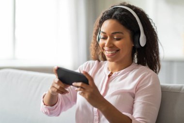 Kaygısız bir Afro-Amerikan milenyumu evde kulaklıklarla telefonundan içeriği izlemeyi sever.