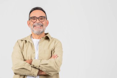 Gözlüklü bir son sınıf öğrencisi kollarını göğsünde kavuşturarak ayakta duruyor. Kendinden emin ve iddialı görünüyor, yüzünde ciddi bir ifadeyle, boşluğu taklit ediyor.