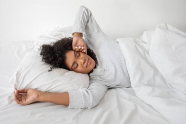 İspanyol kadın beyaz çarşaflı bir yatakta yatıyor. Oda basit ve düzenli, doğal ışık içeri akıyor, uyanıyor. Hanımefendi rahat ve rahat görünüyor, dinlenirken gözleri kapalı..