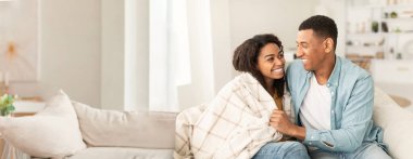 Sıcak ve sevecen Afrikalı Amerikalı çift kanepenin altında battaniyenin altında, fotokopi alanı olan internet afişi için ideal.