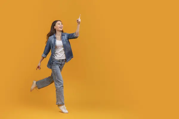 Excited Young Asian Woman Running Pointing Upwards Isolated Orange Background — Stock Photo, Image