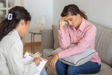 Kafasına dokunan çatık kaşlı düşünceli bir kadın huzur kliniğindeki bir profesyonelden tavsiye alır.