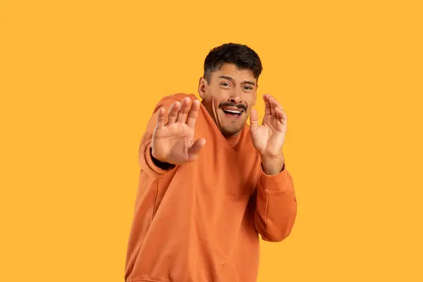 オレンジ色のシャツを着ている男性は 彼の動きを通して何かを表現し 手でジェスチャーしています 彼の手ははっきりと見え ジェスチャーはシーンの焦点です — ストック写真