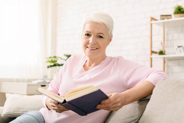 Sakin emeklilik zamanı. Neşeli yaşlı bayan evde kitap okuma, boş alan