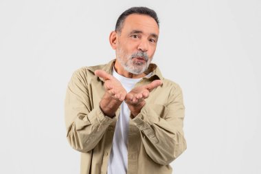 A charismatic elderly man blows a kiss with a hand gesture, showing affection and warmheartedness, isolated on a white background clipart