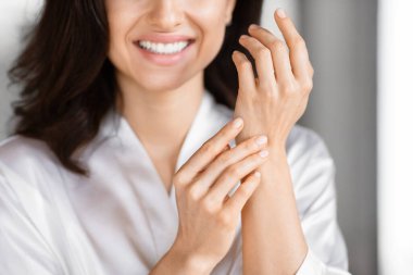 Bu resimde beyaz gömlekli bir kadının el derisini incelediği görülüyor. Banyoda binlerce yıllık cilt bakımına bağlı.