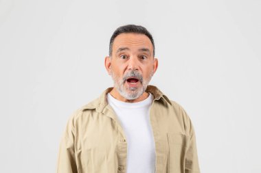A senior man with a look of surprise on his face, eyebrows raised, mouth slightly agape. His eyes are wide, indicating shock or astonishment. He appears taken aback by something unexpected. clipart