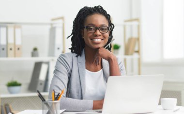 Başarılı bir iş kadınıydı. Laptopta oturan ve modern ofiste gülümseyen afro kız. Metin için Boşluk