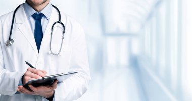 Kaliteli Tıbbi Hizmetler. Hastane koridorunda, kırpılmış resimde, panoramada dururken, üniformalı tanınmayan erkek doktor panoya not alıyor.