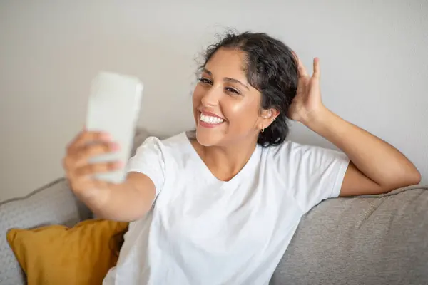 Woman Seated Couch Holding Cell Phone Her Hands She Appears — Stock Photo, Image