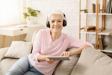Müzik keyfi ve tablet pc kulaklık, video izleme kadın kıdemli boş alan