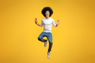 Ahmaklık, turuncu studio arka plan üzerinde havada atlama neşeli bin yıllık adam